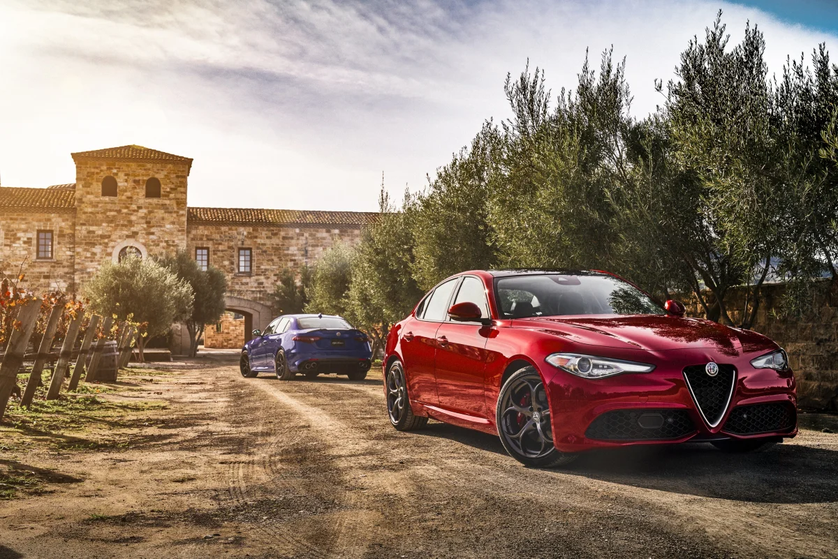 A red Alfa Romeo Giulia against the backdrop of an old Italian villa