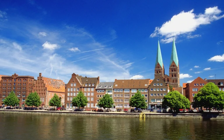 a sunny day in lübeck with a view of st. peter's church, st. peter's church, churches, cities, city, clouds, germany, rivers, canals, streams, sky, trees, waterfronts, marinas, architecture, world