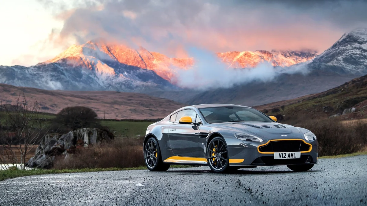 Серый Aston Martin V12 Vantage на фоне заснеженных гор