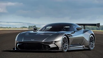 A gray Aston Martin Vulcan on a race track under a cloudy sky