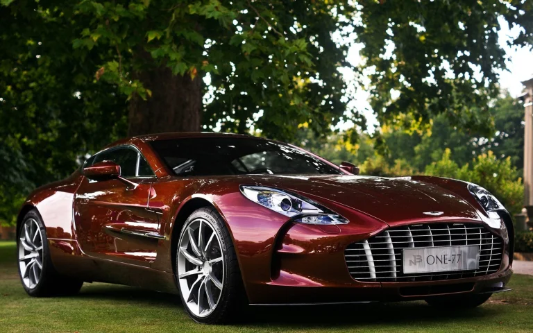 бордовий aston martin one-77 у тіні розлогих дерев, aston martin one-77, aston martin, астон мартін, дерева, диски, колеса, літо, машини, автомобілі, спорткари, суперкари, гіперкари, трава, трави, газони, авто