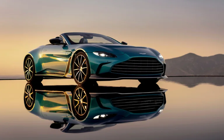 бірюзовий родстер aston martin vantage на тлі гір, aston martin v12 vantage roadster, aston martin, астон мартін, вечір, вечори, сутінки, відображення, гори, вершини, пагорби, диски, колеса, захід сонця, кабріолети, машини, автомобілі, спорткари, фари, авто