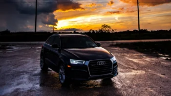 Черный кроссовер Audi Q3 на фоне яркого закатного неба