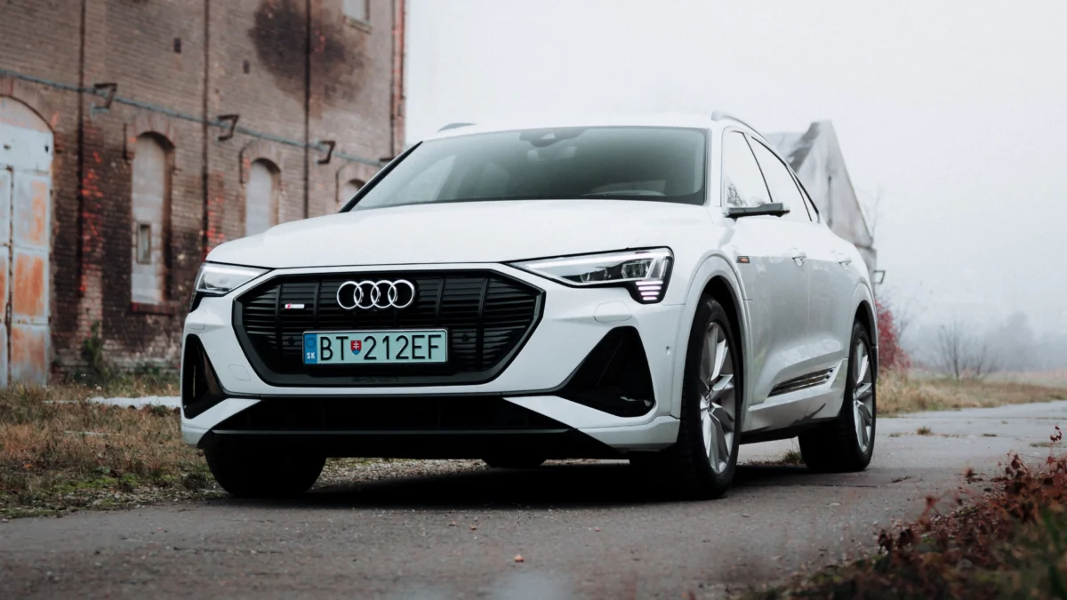 Белый кроссовер Audi e-tron на фоне старинного кирпичного здания