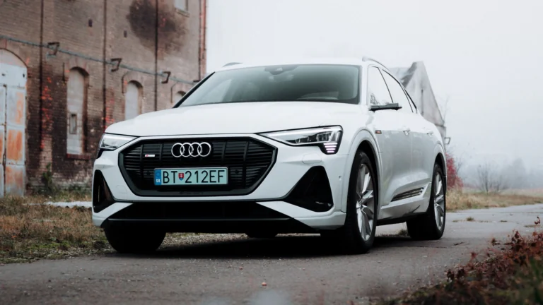 Белый кроссовер Audi e-tron на фоне старинного кирпичного здания