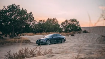 Седан Audi A4 на песчаных дюнах в лучах заката
