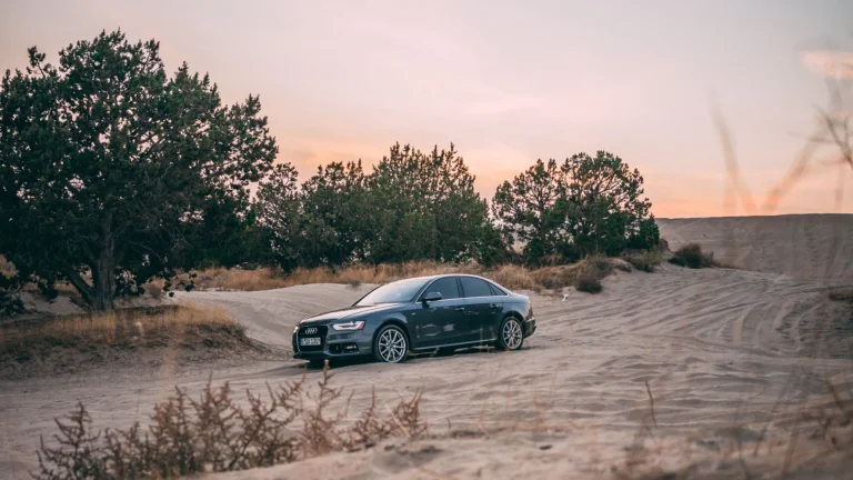 Седан Audi A4 на песчаных дюнах в лучах заката