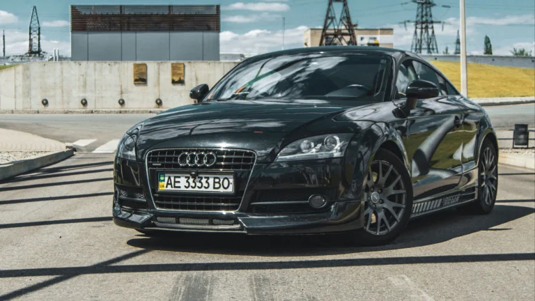 Черное купе Audi TT на фоне индустриального пейзажа
