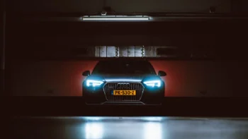 Audi A4 Allroad с включенными фарами в темном паркинге