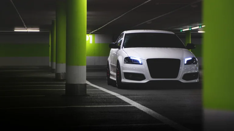 Белый хэтчбек Audi в свете ламп подземного паркинга