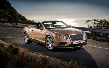 золотистий bentley continental gt convertible на прибережній дорозі, bentley continental gt convertible, bentley, бентлі, гори, вершини, пагорби, диски, колеса, дороги, шляхи, траси, шосе, магістралі, автостради, проспекти, проїзди, захід сонця, кабріолети, машини, автомобілі, море, моря, пейзажі, сонце, сонячні промені, сонячне світло, авто
