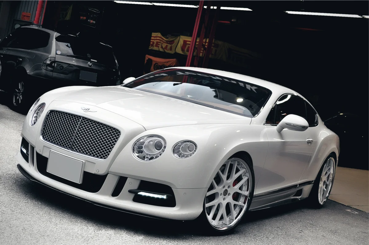 A snow-white Bentley Continental GT in a garage bay
