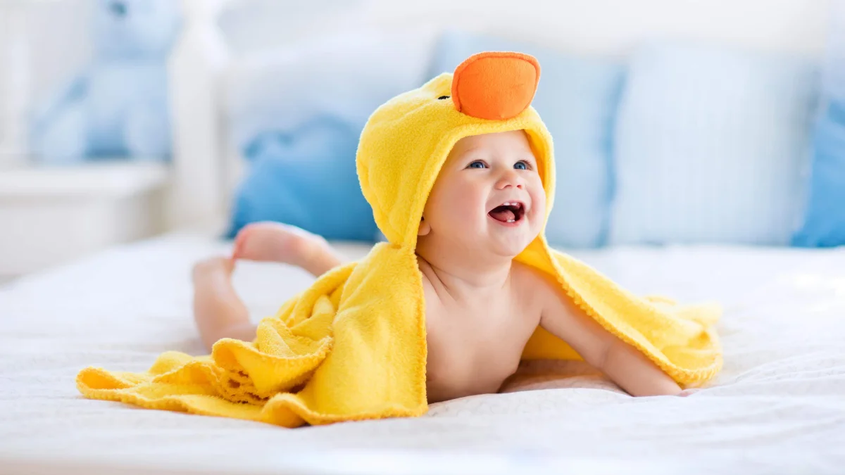 A happy baby in a yellow towel with a duck-shaped hood