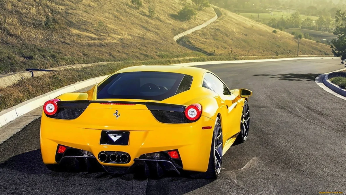 A yellow Ferrari 458 Italia on a winding mountain road