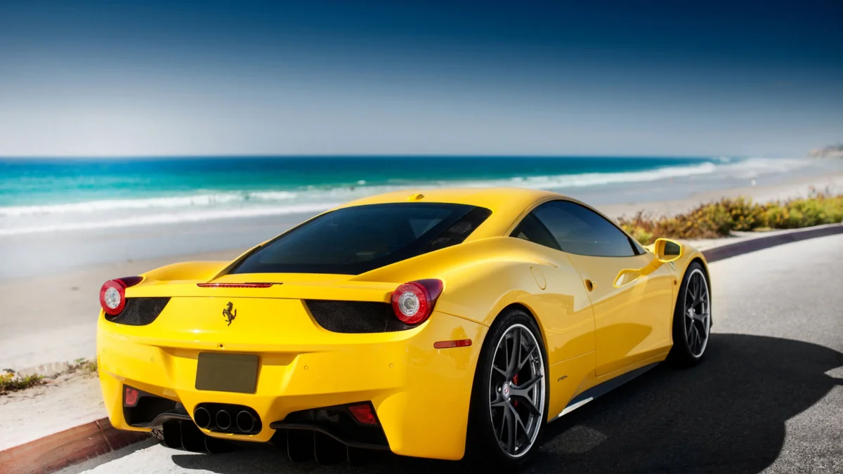 A yellow Ferrari 458 Italia against the backdrop of the ocean coastline