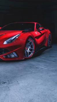 A scarlet Ferrari F12berlinetta sports car in the dim light of the garage