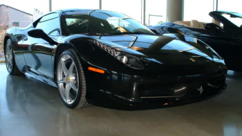 A black Ferrari 458 Italia in a brightly lit showroom