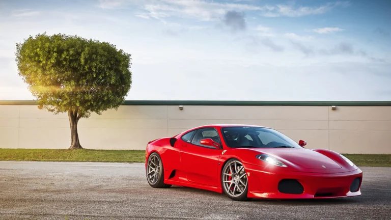 A bright red Ferrari F430 against the backdrop of a solitary tree