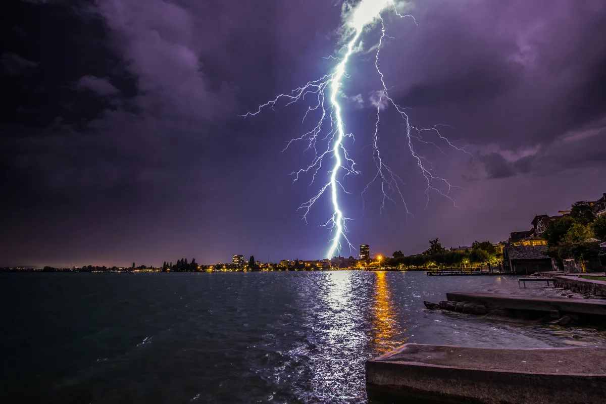 A bolt of lightning over the nighttime coastline of a Swiss city