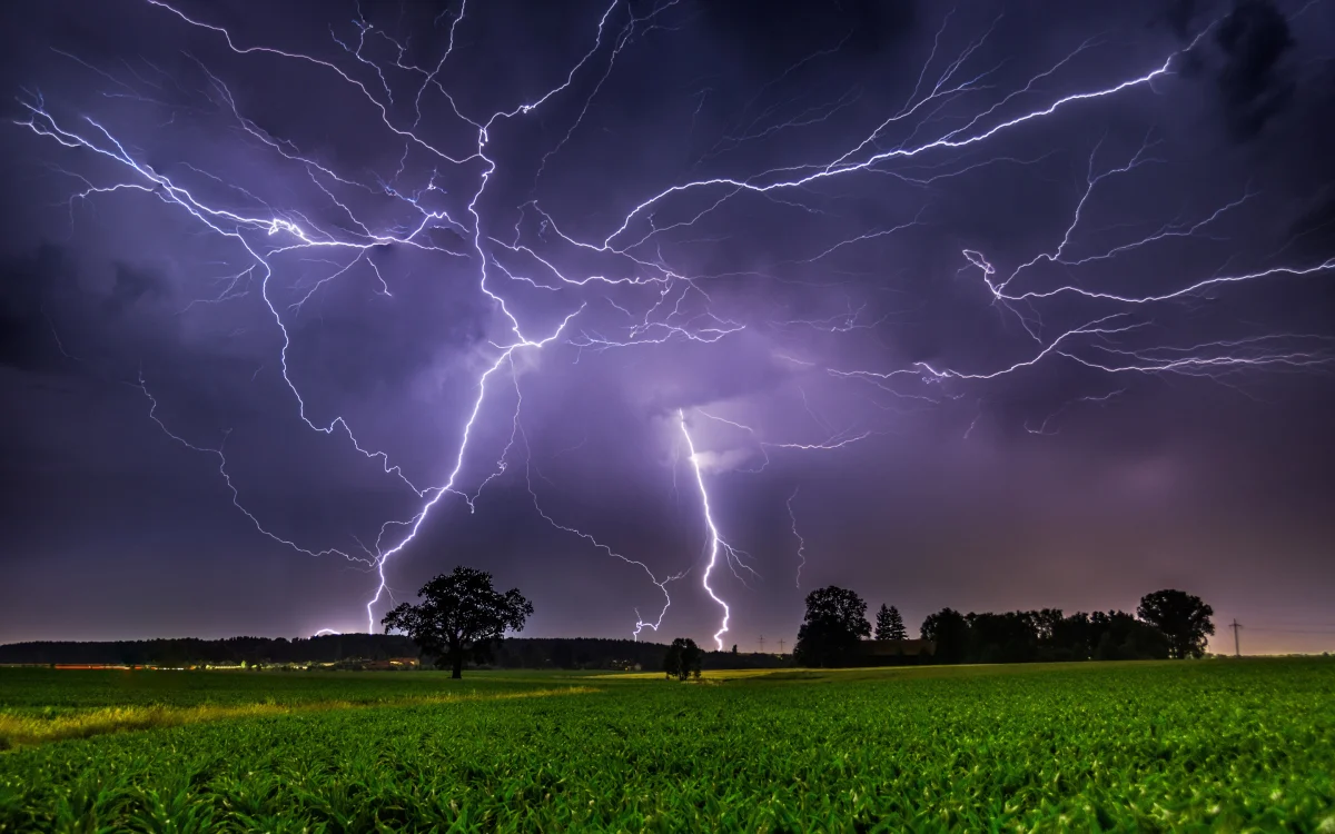 Lightning strikes over a field at night