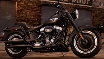 Черный мотоцикл Harley-Davidson Fat Boy на фоне кирпичной стены