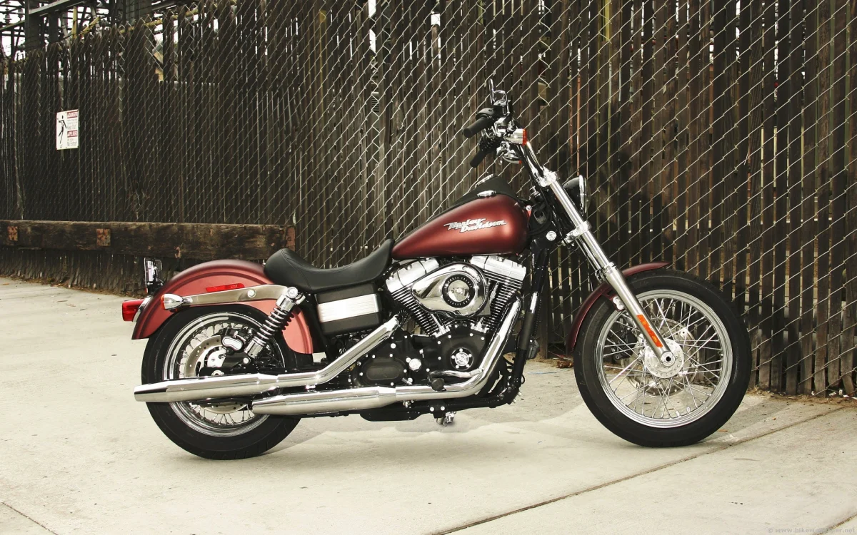 Бордовий мотоцикл Harley-Davidson Dyna біля сітчастого паркану