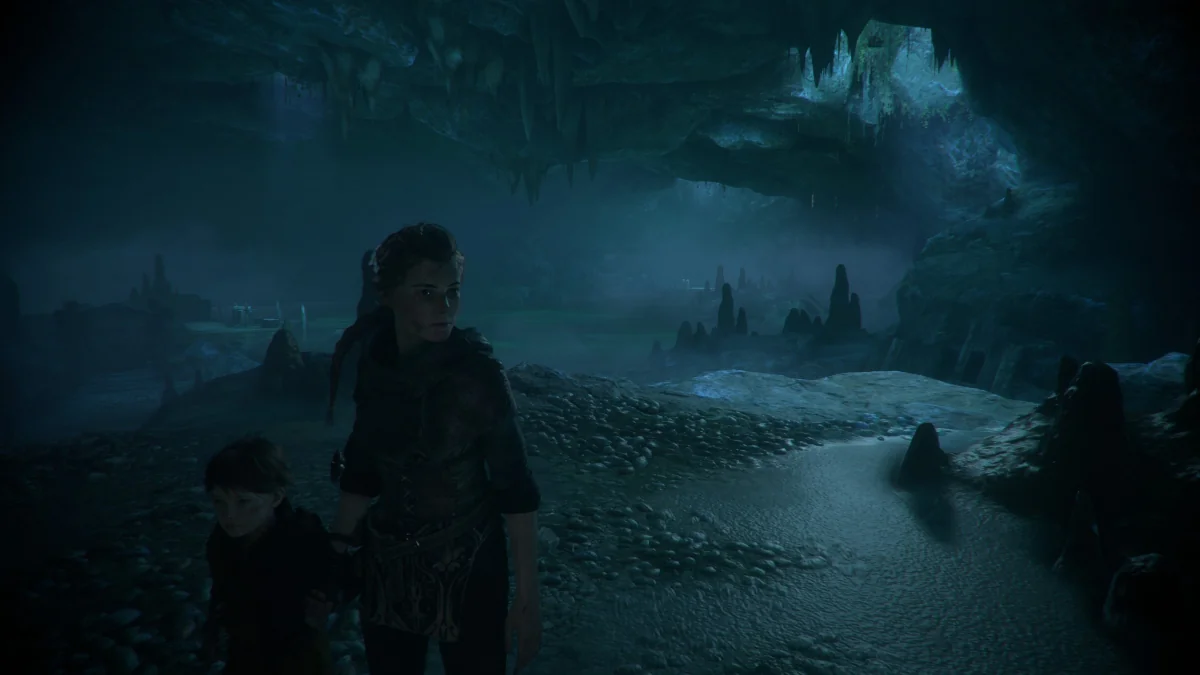 Amicia and Hugo in the gloomy depths of a cave from "A Plague Tale: Requiem"