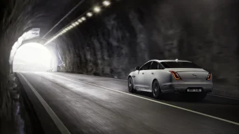 Білий Jaguar XJ, що виїжджає з темного гірського тунелю
