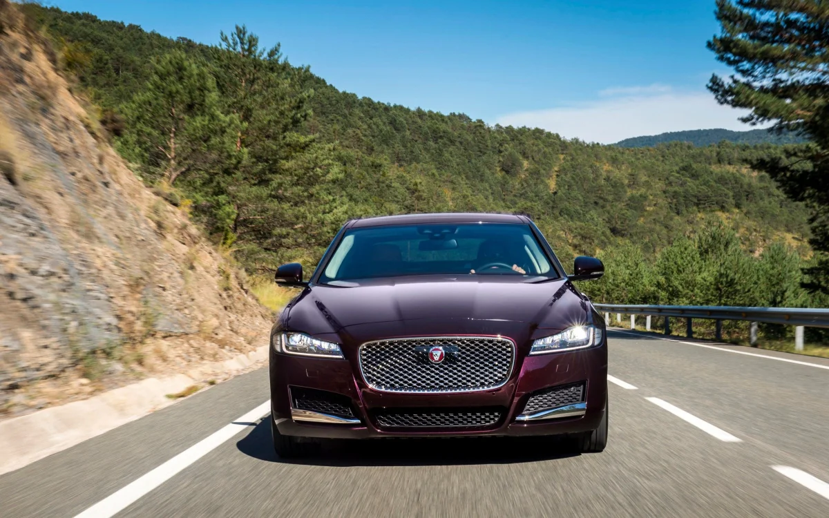 Темно-бордовый Jaguar XF на извилистой горной дороге