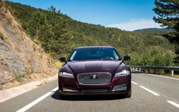 Темно-бордовый Jaguar XF на извилистой горной дороге