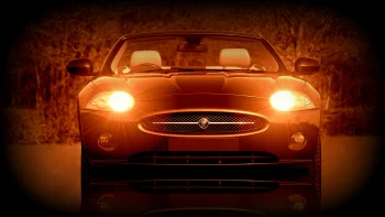 Jaguar XK с включенными фарами в сумерках