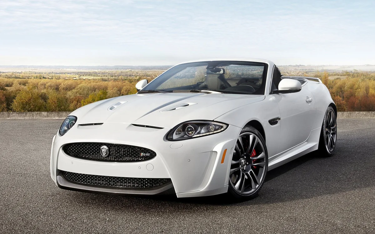 A snow-white Jaguar XKR-S Convertible against the backdrop of an autumn landscape