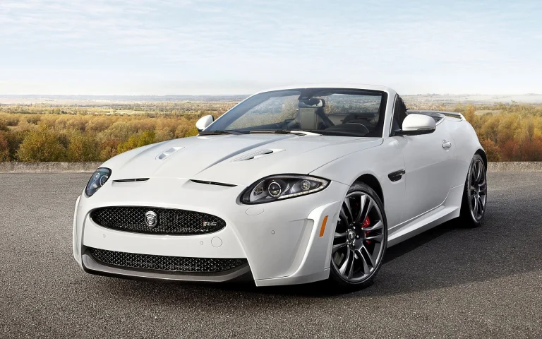 A snow-white Jaguar XKR-S Convertible against the backdrop of an autumn landscape