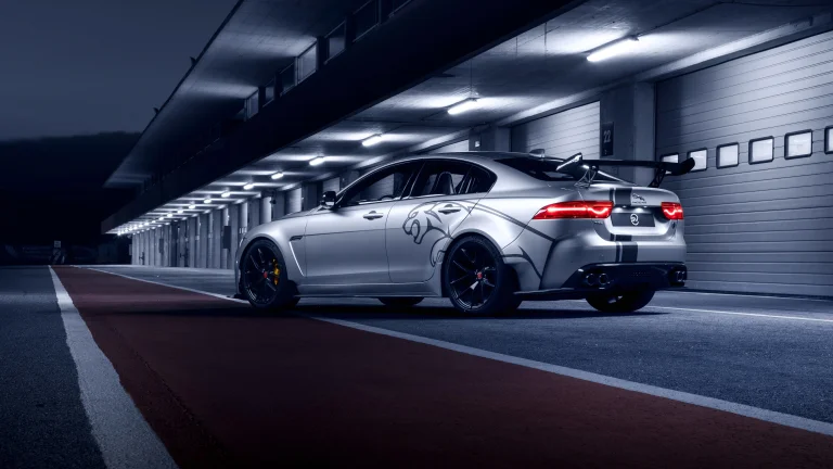 A silver Jaguar XE SV Project 8 under the lights of a racetrack at night