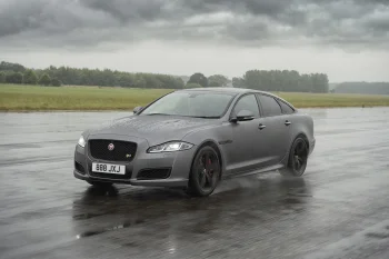 Серый Jaguar XJ на мокром асфальте под пасмурным небом