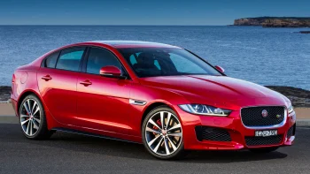 A red Jaguar XE against the backdrop of the blue ocean