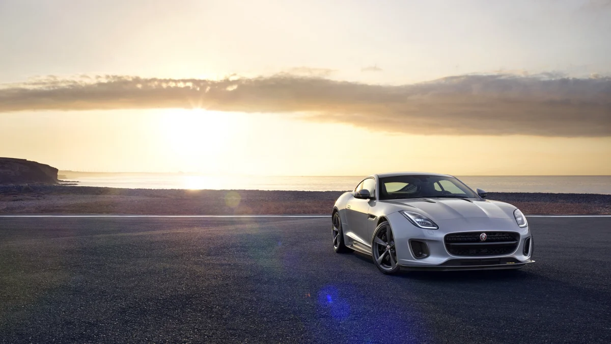 Серебристый Jaguar F-Type на фоне закатного морского побережья