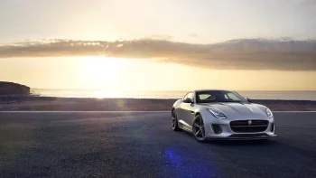 Серебристый Jaguar F-Type на фоне закатного морского побережья