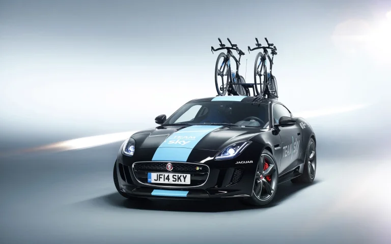 Черный Jaguar F-Type с велосипедами Team Sky на крыше