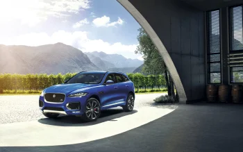 A blue Jaguar F-Pace against a backdrop of sun-drenched mountain slopes