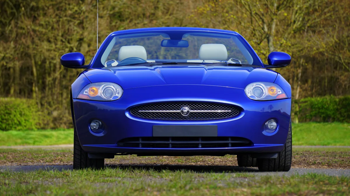 Синий Jaguar XK на фоне весеннего парка