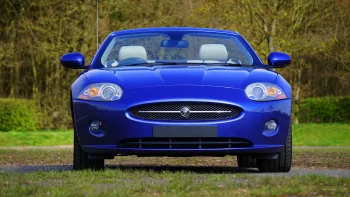 Синий Jaguar XK на фоне весеннего парка