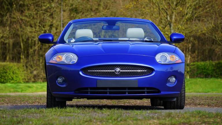 Синий Jaguar XK на фоне весеннего парка