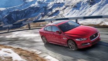A red Jaguar XE on a snow-covered mountain road