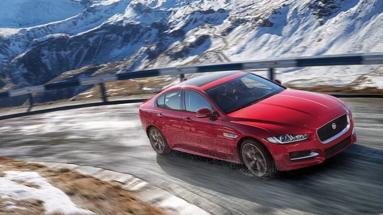 A red Jaguar XE on a snow-covered mountain road