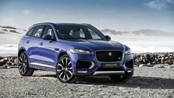 A blue Jaguar F-Pace against the backdrop of a sandy coastline