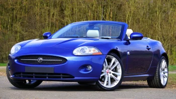 Синій кабріолет Jaguar XK на тлі весняного лісу