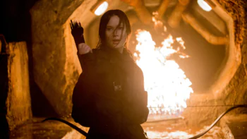 Katniss Everdeen in a tunnel with fire in the background