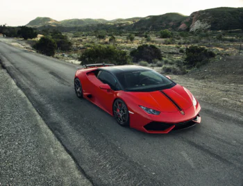 Червоний Lamborghini Huracan на безлюдній дорозі в горах