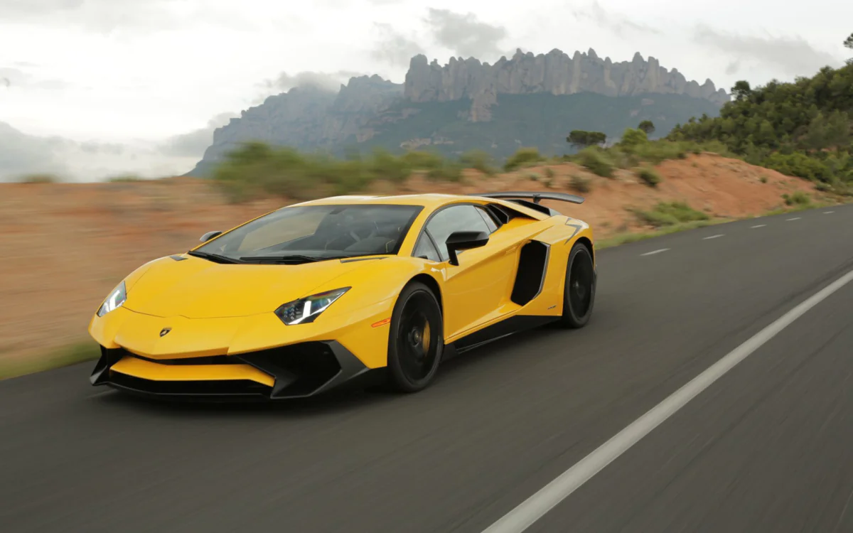A yellow Lamborghini Aventador SV on a mountain road in Spain